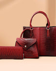 Three-piece red crocodile-textured faux leather bag set featuring a spacious tote bag with sturdy handles, a compact mini handbag with a stylish flap closure, and a matching wallet. The set exudes elegance with its bold red color and sophisticated crocodile pattern, perfect for various occasions.