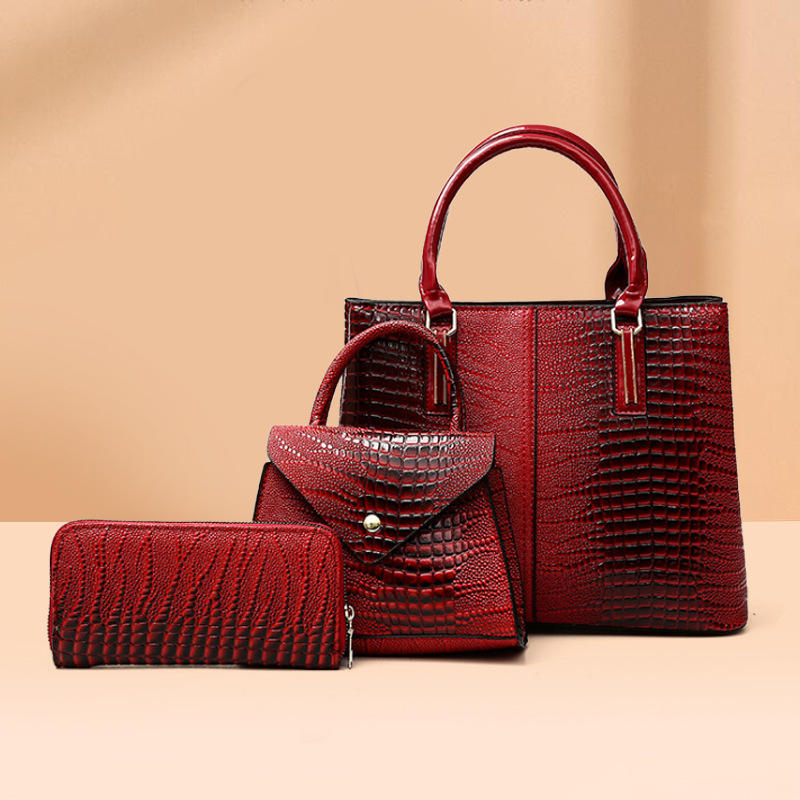 Three-piece red crocodile-textured faux leather bag set featuring a spacious tote bag with sturdy handles, a compact mini handbag with a stylish flap closure, and a matching wallet. The set exudes elegance with its bold red color and sophisticated crocodile pattern, perfect for various occasions.