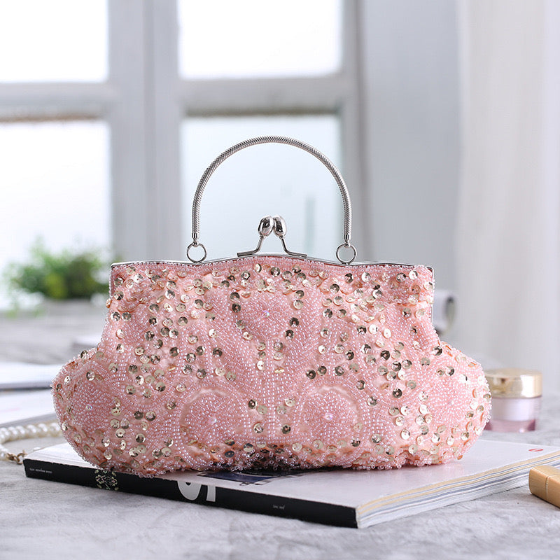 This is an image of a pink clutch purse. The clutch features a sleek and shiny silver exterior with a delicate chain strap. It is a stylish accessory, perfect for adding a touch of sophistication to any evening outfit.
